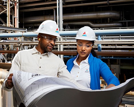 Two employees looking over blueprints at a power plant