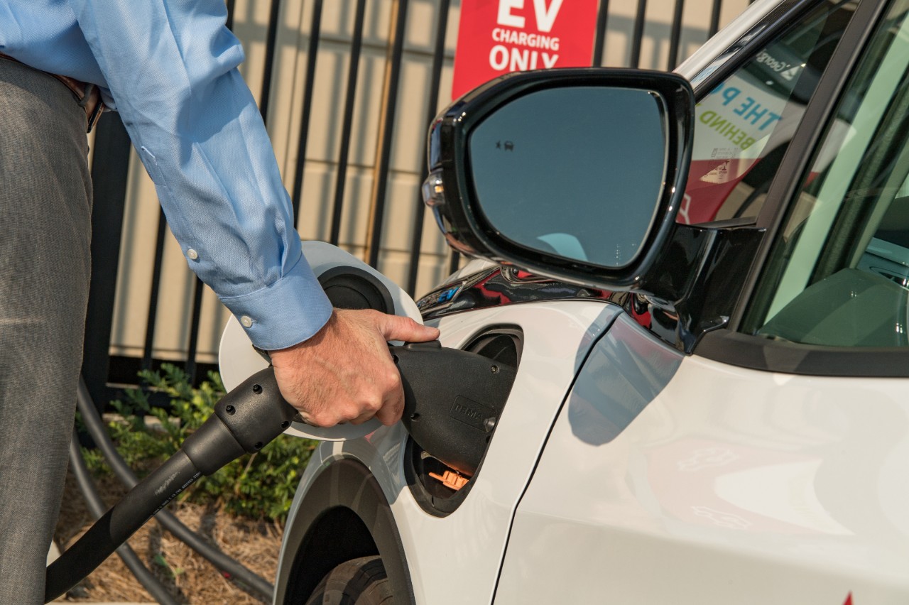 Man charging electric vehicle at clean energy EV charging station  