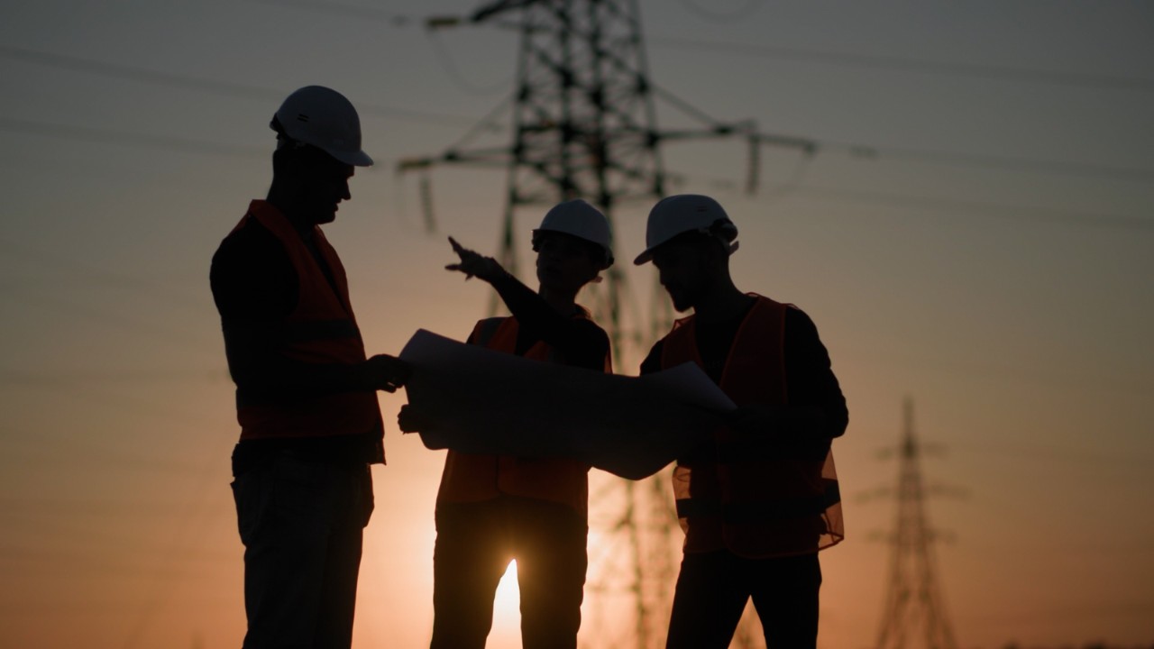 Two employees looking over blueprints at a power plant