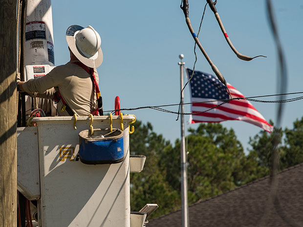 American flag in the background as a Georgia Power lineman makes repairs