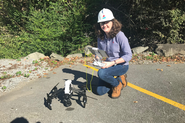 Grace Elliot, our first female drone pilot, poses in front of a drone.
