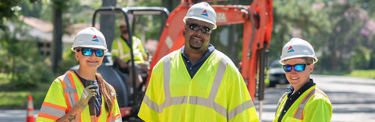 Gas workers smiling while digging and laying down pipeline