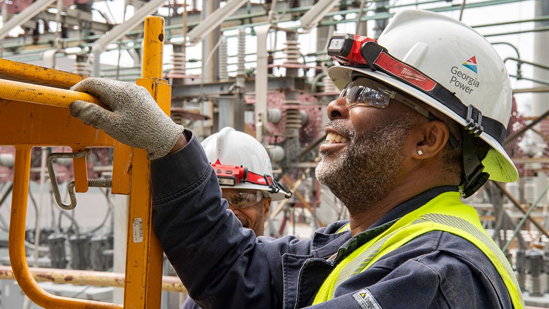 Power plant engineer in Georgia Power hardhat looking up and smiling