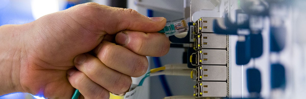 Person plugging in a fiber cable
