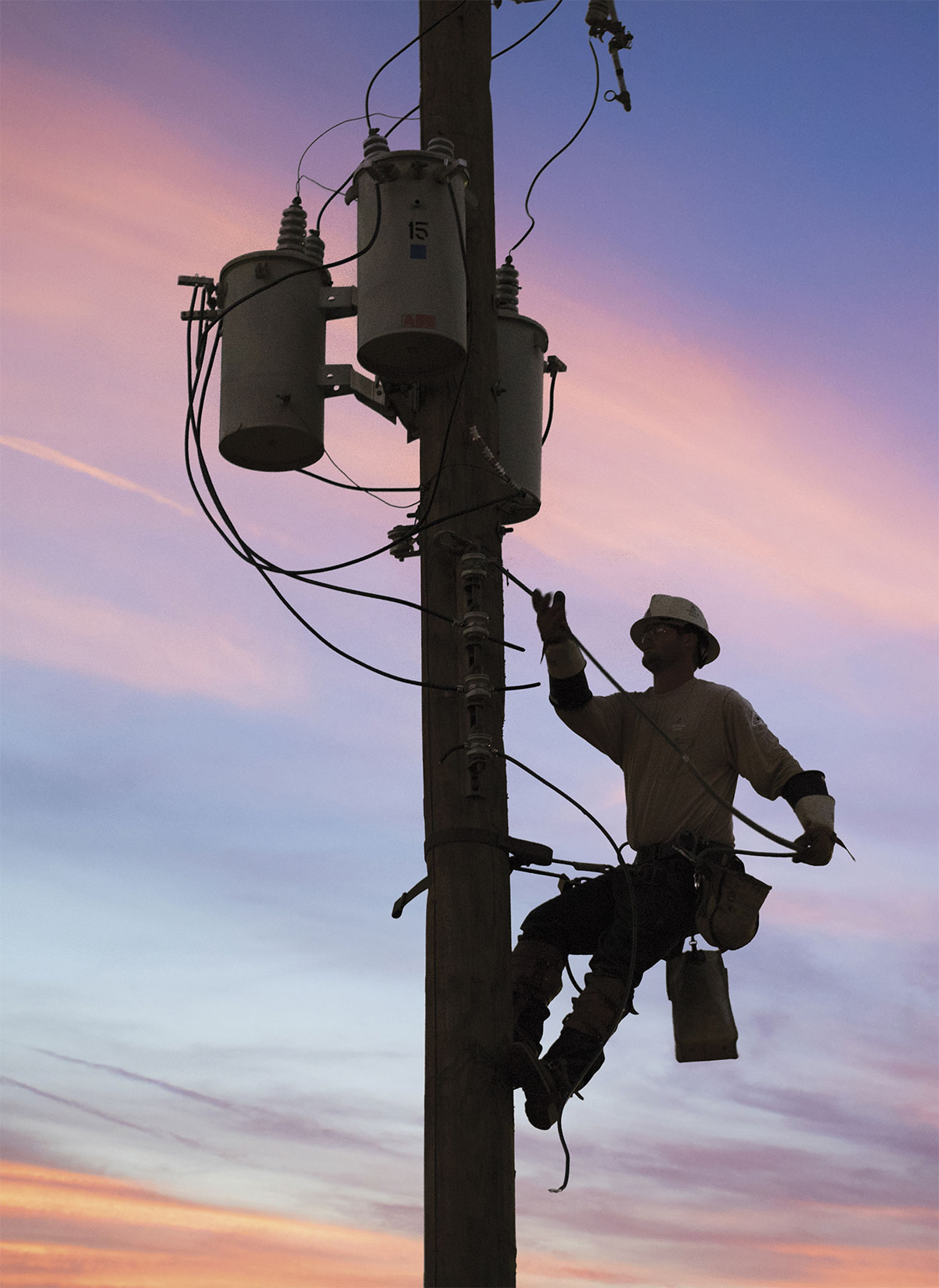 Silhouette of lineman on power pole
